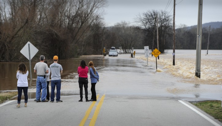 Bystanders watch the Flint River flow over Old Hwy. 431 on Saturday, Dec. 26, 2015, in Owens Cross Roads, near Huntsville, Ala. The flooding is the result of heavy downpours that have been thrashing the southeastern U.S. since Wednesday, bringing record rainfalls in some areas. (AP Photo/John Amis)