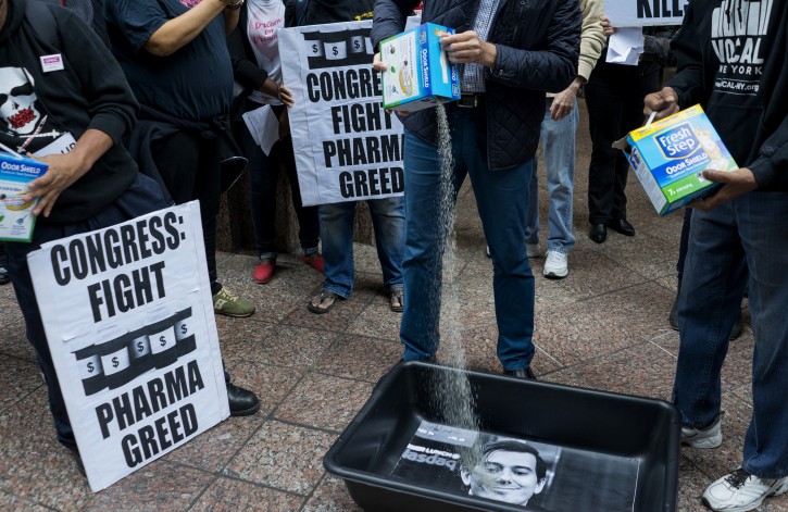 FILE - In this Oct. 1, 2015 file photo, AIDS activists pour cat litter on an image of Turing Pharmaceuticals CEO Martin Shkreli in a makeshift cat litter pan during a protest highlighting pharmaceutical drug pricing in New York.  Shkreli, the former hedge fund manager under fire for buying a pharmaceutical company and ratcheting up the price of a life-saving drug, is in custody following a securities probe, Thursday, Dec. 17, 2015.  (AP Photo/Craig Ruttle)