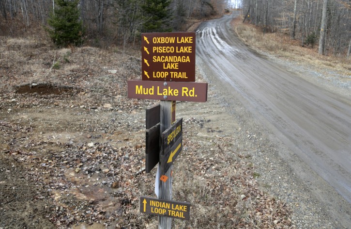 Signs give directions to various locales on a seasonal road that is used by snowmobilers during the winter months on Tuesday, Dec. 8, 2015, in Lake Pleasant, N.Y. Some Northeasterners are beginning to wonder if a white Christmas may just be a dream, and business owners who rely on snow are starting to worry if warm weather could lead to a nightmare winter. (AP Photo/Mike Groll)