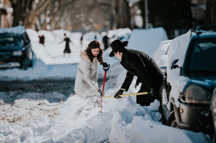 An Orthodox Jewish couple clean up snow near their buried vehicle in the Borough Park section of Brooklyn, NY on Jan, 24 2016 (Eli Wohl/VINnews.com)