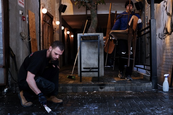 An Israeli man cleans outside a pub on Dizengoff Street in central Tel Aviv, on January 04, 2016, a few days after two people were killed in a shooting at the bar and several injured. Israeli security forces are still searching forthe shooter who disappeared in the Tel Aviv area. Photo by Ben Kelmer/Flash90 