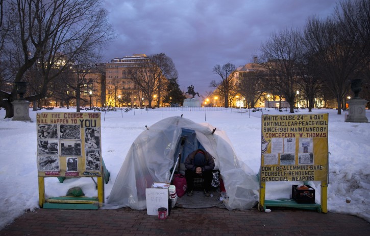 CraigThompson sits in the anti-nuclear-proliferation vigil stationed along Pennsylvania Avenue on the edge of Lafayette Square Park across from the White House in Washington, early Tuesday, Jan. 26, 2016. A white sign in front reads "Concepcion RIP." Concepcion Picciotto, the protester who maintained a peace vigil outside the White House for more than three decades, a demonstration widely considered to be the longest-running act of political protest in U.S. history, has died. The Washington Post report Picciotto died Monday, Jan. 25, 2016, at a housing facility for homeless women. She was believed to be 80. (AP Photo/Carolyn Kaster)