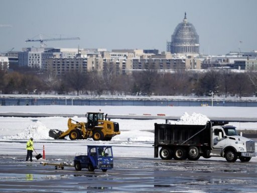 Workers remove snow on the tarmac at Ronald Reagan National Airport, with the U.S. Capitol dome seen behind, Sunday, Jan. 24, 2016 in Arlington, Va. Millions of Americans began digging out Sunday from a mammoth blizzard that set a new single-day snowfall record in Washington and New York City. (AP Photo/Alex Brandon) (Photo: Alex Brandon / AP)