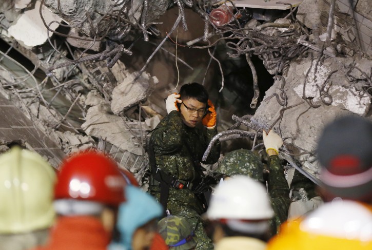 An Army soldier listens for signs of life in a collapsed building from an earthquake in Tainan, Taiwan, Sunday, Feb. 7, 2016. Rescuers on Sunday found signs of live within the remains of a high-rise residential building that collapsed in a powerful, shallow earthquake in southern Taiwan that killed over a dozen people and injured hundreds. (AP Photo/Wally Santana)