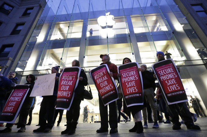 Protesters carry placards outside an Apple store Tuesday, Feb. 23, 2016, in Boston. (AP Photo/Steven Senne)