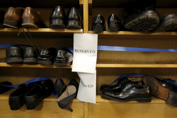 Shoes removed by visitors out of reverence sit on a shelf marked 