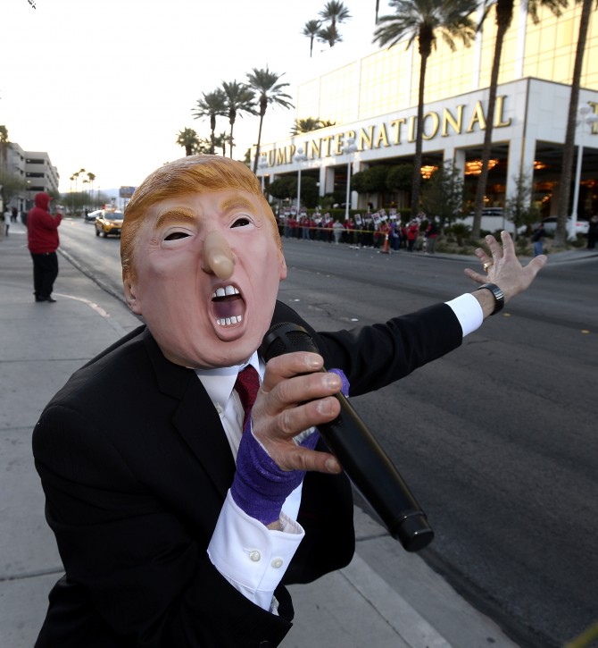  Dr. Gil Mobley, wearing a mask resembling US Republican presidential candidate Donald Trump, sings an original song about Trump, as members of the Culinary Workers Union (background) protest outside the Trump-owned Hotel Las Vegas in Las Vegas, Nevada, USA, 23 February 2016.  EPA/MIKE NELSON