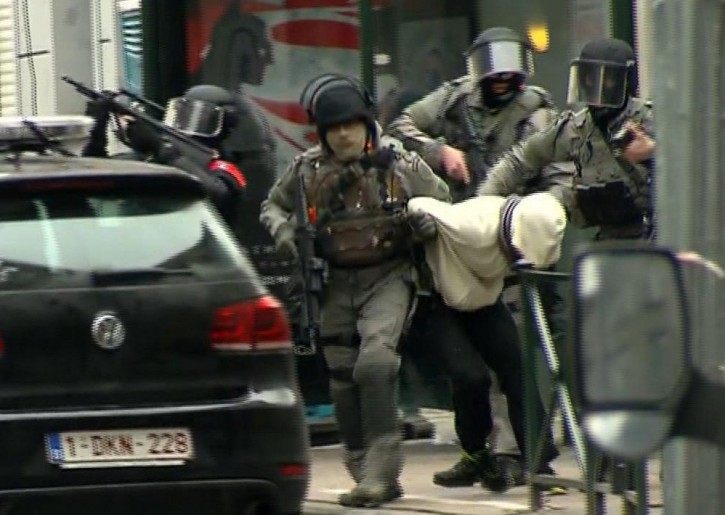 In this framegrab taken from VTM, armed police officers escort Salah Abdeslam to a police vehicle during a raid in the Molenbeek neighborhood of Brussels, Belgium, Friday March 18, 2016. AP