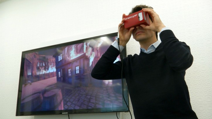 This Feb. 2, 2016 image made from video shows Timelooper co-founder Yigit Yigiter looking through a Google cardboard virtual reality headset as he sees a recreation of the Great Fire of London in 1666. The Timelooper app allows users to experience key moments in London history with just a smartphone and a cardboard headset. (AP Photo)