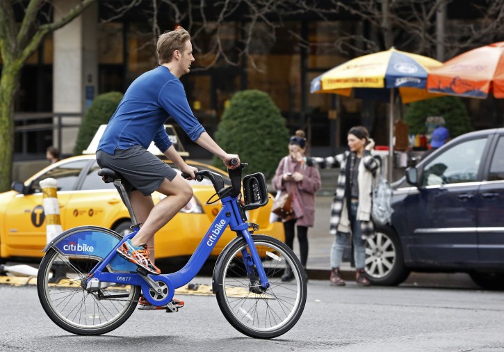FILE - In this Dec. 24, 2015 file photo, a man wearing shorts, sneakers and no socks rides a rental bike through a downtown Manhattan street on Christmas Eve. Federal meteorologists say the winter that has just ended was the hottest in U.S. records, thanks to the combination of El Nino and man-made global warming. (AP Photo/Kathy Willens, File)