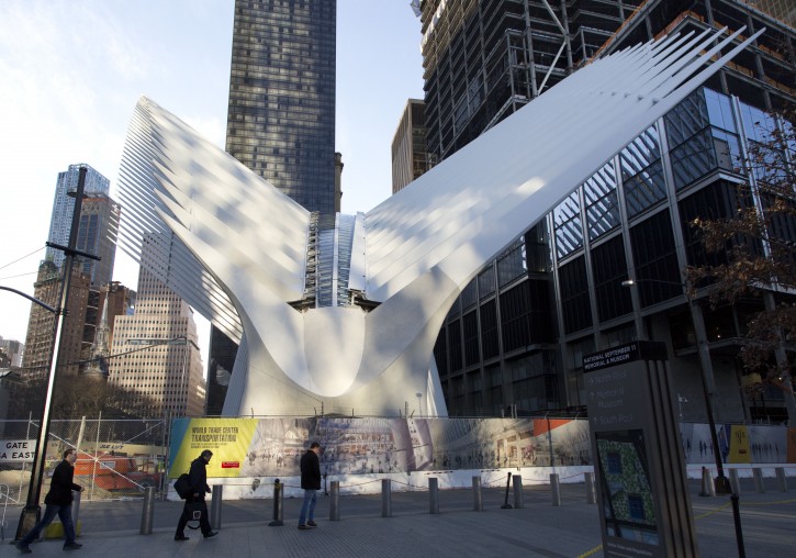 People walk past the World Trade Center Transportation Hub, Thursday, March 3, 2016, in New York. Officials say the transit hub's cathedral-like pavilion will partially open to the public Thursday afternoon.(AP Photo/Mark Lennihan)