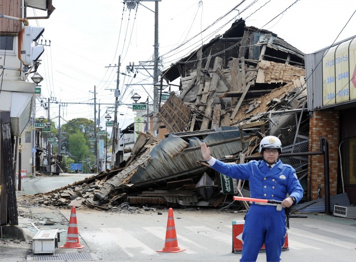 A police officer stands guard in front of a house destroyed by an earthquake in Mashiki, Kumamoto prefecture, southern Japan Saturday, April 16, 2016. A powerful earthquake struck southern Japan early Saturday, barely 24 hours after a smaller quake hit the same region. (Ryosuke Uematsu/Kyodo News via AP)