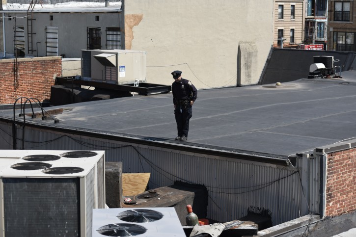 FILE - A Police officer stands guard on the rooftop above HSBC bank on 13th Ave where a thief dug a hole and made off with nearly 300K worth of valuables. (Eli Wohl/VINnews.com)