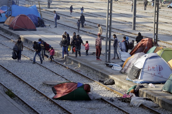 Migrants cross tracks at a railway station near a makeshift camp at the northern Greek border point of Idomeni, Greece, Wednesday, April 20, 2016. AP