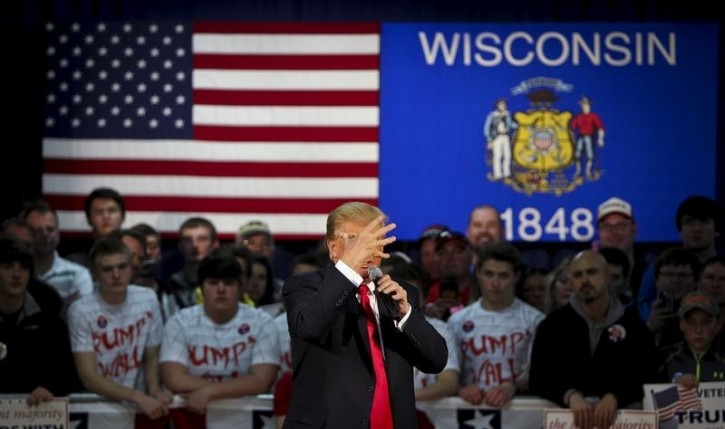 Republican U.S. presidential candidate Donald Trump covers his face, in reference to what he says are politicians who wear a "brand" of special interests, at a campaign town hall event in Wausau, Wisconsin April 2, 2016.   REUTERS/Ben Brewer 