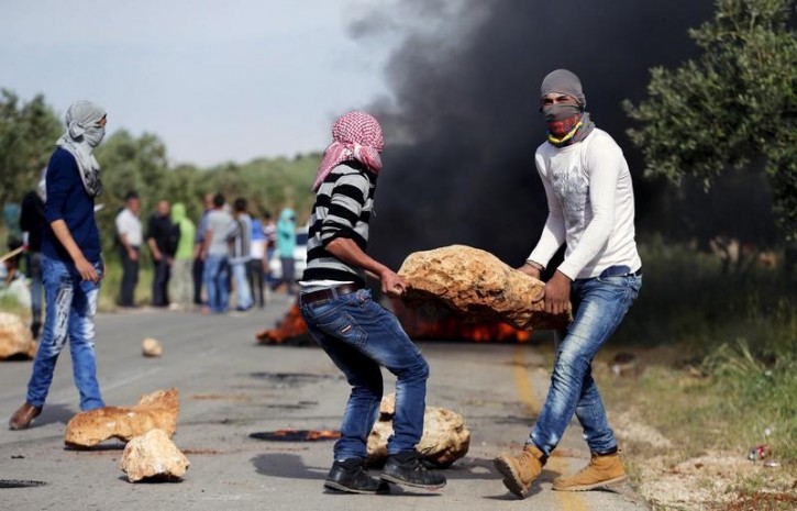 FILE - Palestinian protesters carry a rock during clashes with Israeli troops in the West Bank village of Duma near Nablus, April 5, 2016. REUTERS/Ammar Awad  