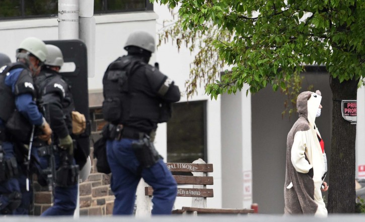 A man wearing a full animal costume and surgical mask walks out of a TV station in Baltimore, Thursday, April 28, 2016. Baltimore police say a department sniper shot the man, who police say walked into a TV station displaying what appeared to be an explosive device on his chest. (Kenneth K. Lam/The Baltimore Sun via AP) 