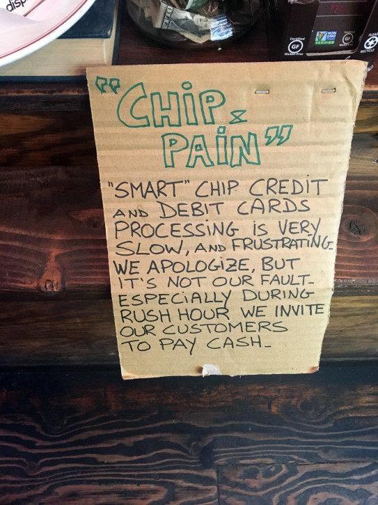 This December 2015 photo shows a sign posted at a coffee shop in New York. Visa says its improving its smart chip-embedded cards, which have been the source of grumbling from businesses and customers forced to wait for transactions to go through. The company said Tuesday, April 19, 2016, that Quick Chip for EMV will let customers dip and remove cards, usually in two seconds or less, without waiting for purchases to be finalized. (AP Photo/Joseph Pisani)