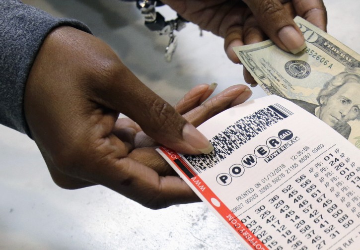 FILE - In this Jan. 13, 2016 file photo, a clerk hands over a Powerball ticket for cash at Tower City Lottery Stop in Cleveland. AP