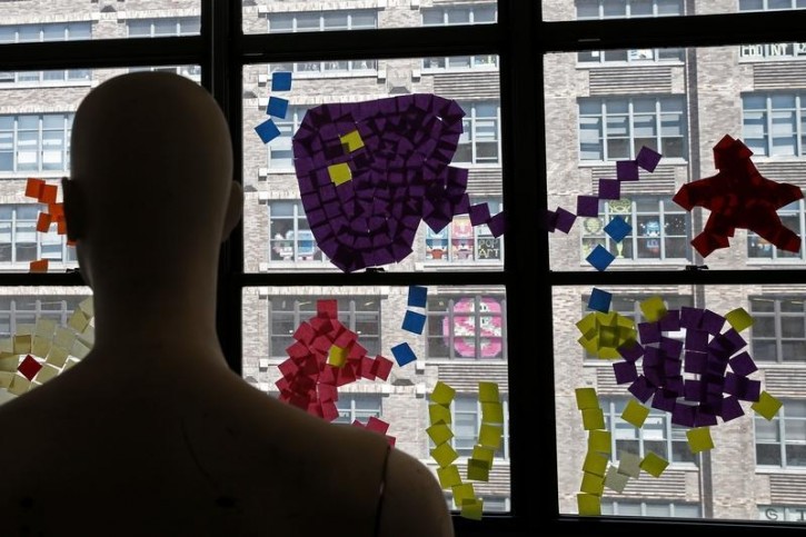 A mannequin stands near images created with Post-it notes in windows at 200 Hudson street in lower Manhattan, New York, U.S., May 18, 2016, where advertising agencies and other companies have started what is being called a "Post-it note art war" with employees in buildings across Canal street from each other creating colorful images in their windows with Post-it notes. REUTERS/Mike Segar 