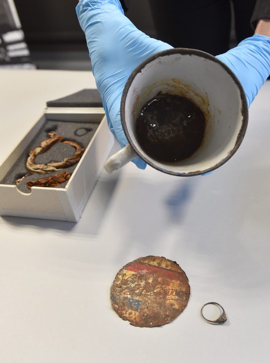 Hanna Kubik from the Collections department of the Auschwitz-Birkenau State Museum presents an enamel mug with a double bottom in which the jewellery was found at a press conference at the Auschwitz-Birkenau State Museum in Oswiecim, Poland, 19 May 2016. Auschwitz Museum curators discovered the jewellery, a gold ring and necklace, during maintenance works on kitchenware items looted by German forces from the people who arrived at the Auschwitz-Birkenau camp during the World War II. The jewellery was hidden in a double bottom enamel mug and were discovered after the fake bottom deteriorated over time. the jewellery will be documented and secured in the Auschwitz-Birkenau State Museum.  EPA/JACEK 