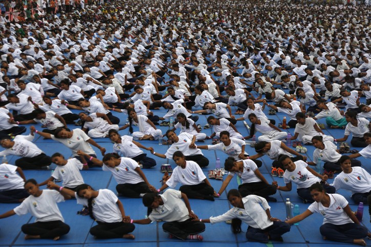 Indians holds each others hands as they attempt to create a record of longest human yoga chain with more than 8000 participants at an event to celebrate International Yoga Day in Ahmadabad, India, Tuesday, June 21, 2016. Millions of yoga enthusiasts are bending their bodies in complex postures across India as they take part in a mass yoga program to mark the second International Yoga Day. (AP Photo/Ajit Solanki)