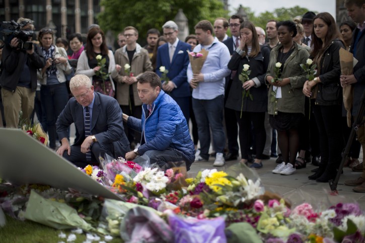 Staff from Britain's opposition Labour Party including at the front MP John Cryer, left, the Chair of the Parliamentary Labour Party and Iain McNicol, right, the party's General Secretary pay their respects after placing floral tributes for their colleague Jo Cox, the 41-year-old British Member of Parliament shot to death yesterday in northern England, on Parliament Square outside the House of Parliament in London, Friday, June 17, 2016. The married mother of two young children was shot to death Thursday afternoon in her constituency near Leeds, in northern England. Thomas Mair, 52, was arrested Thursday on suspicion of killing Cox, outside a library. (AP Photo/Matt Dunham)