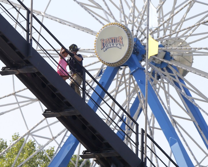 An Oklahoma City firefighter walks down a roller coaster with a child after the coaster stalled at the to of the ride at Frontier City in Oklahoma City on Wednesday, June 29, 2016. (Bryan Terry/The Oklahoman via AP)