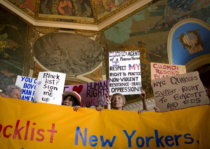 People hold signs during a rally in the War Room at the state Capitol on Wednesday, June 15, 2016, in Albany, N.Y. Critics of Israel's treatment of Palestinians protested Gov. Andrew Cuomo's executive order prohibiting state investments in any company that supports a boycott of Israel. (AP Photo/Mike Groll)