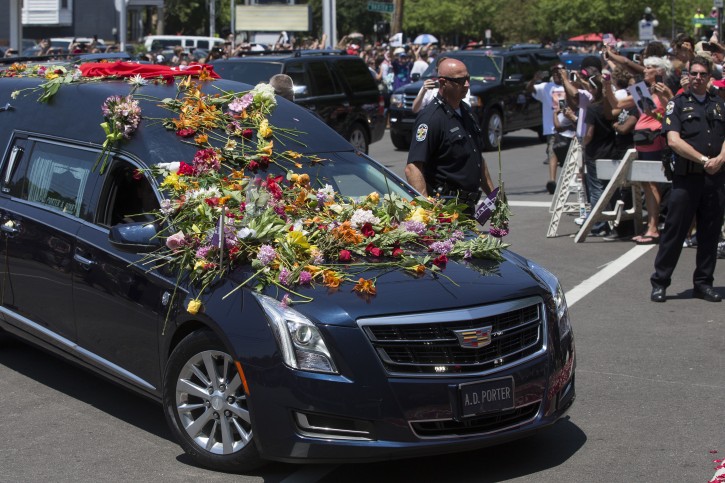 Flowers pile up on the hearse carrying Muhammad Ali spectators watch his funeral procession enter Cave Hill Cemetery, Friday, June 10, 2016, in Louisville, Ky. (AP Photo/John Minchillo)