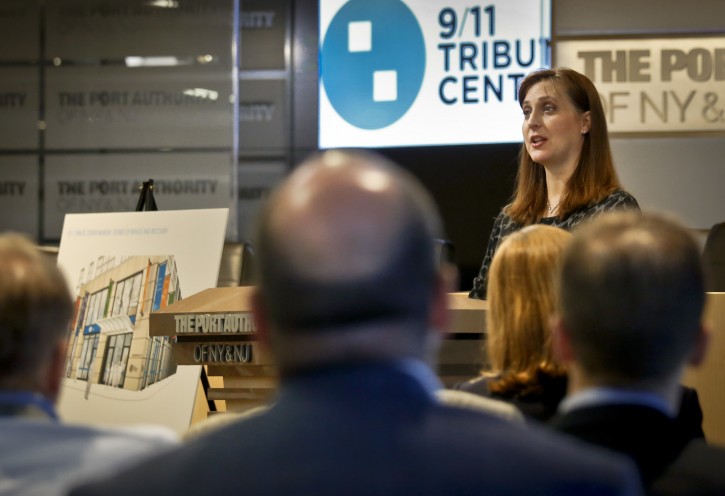 FILE - Jennifer Adams-Webb, right, CEO and co-founder for the September 11 Tribute Center, stands next to a rendering of the center's new museum, left, during a press conference, Tuesday, June 21, 2016, in New York. The Sept 11 Tribute Center, an exhibition center depicting events of 9/11, reopened Monday in the new expanded location near the World Trade Center. (AP Photo/Bebeto Matthews)