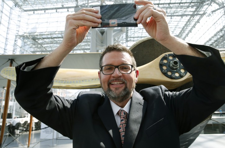 American Philatelic Society executive director Scott D. English holds an "Inverted Jenny," a 1918 stamp stolen in 1955, that is finally being returned to its rightful owner, featuring an airplane printed upside-down, after it was officially handed over during the World Stamp Show, Thursday, June 2, 2016, at the Jacob Javits Center in New York. (AP Photo/Kathy Willens)