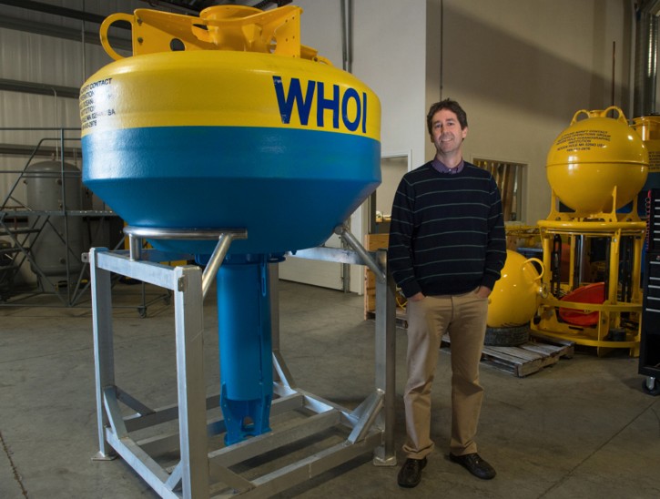 In this Nov. 9, 2015 photo provided by the Wildlife Conservation Society, Dr. Mark Baumgartner of the Woods Hole Oceanographic Institution stands next to a whale bouy, left, a high-tech acoustic device that will eavesdrop on the songs of the whales, in Woods Hole, Mass. Scientists have deployed the buoy 22 miles off the coast of New York's Fire Island to monitor several species of great whales in "near real-time." With the information, scientists at Woods Hole teamed with the Wildlife Conservation Society's Ocean Giants Program in New York hope to better understand and safeguard the whales' movements near two busy shipping lanes entering New York Harbor. (Wildlife Conservation Society, Julie Larsen Maher via AP)