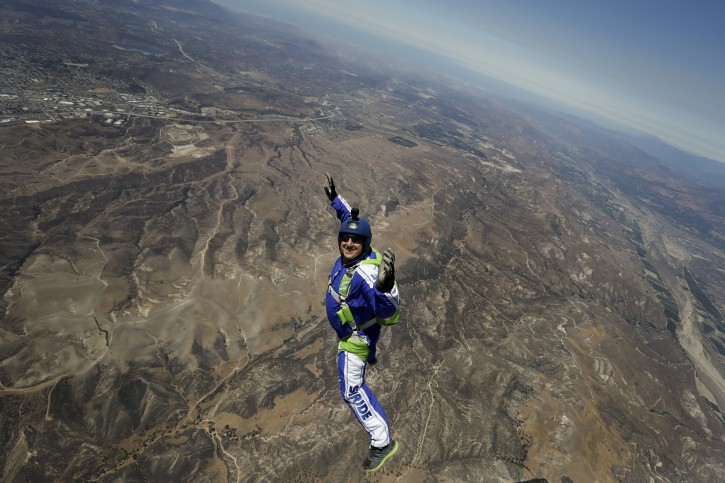 In this Monday, July 25, 2016 photo, skydiver Luke Aikins smiles as he jumps from a helicopter during his training in Simi Valley, Calif. After months of training, this elite skydiver says he's ready to leave his chute in the plane when he bails out 25,000 feet above Simi Valley, Calif. on Saturday. Thatâs right, no parachute, no wingsuit and no fellow skydiver with an extra one to hand him in mid-air. (AP Photo/Jae C. Hong)