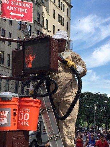 In this July 15, 2015 photo provided by the New York City Police Department, Detective Daniel Higgins suctions up some bees left over from a swarm that took over a pedestrian traffic light in Manhattan the previous day along the route of the Puerto Rican DayParade in New York. Higgins main NYPD job is as a counterterrorism expert, but he is also part of a special team of officers that responds to emergency calls reporting swarms of bees that suddenly cluster in spots around New York City. (NYPD/@nypdbees via AP)