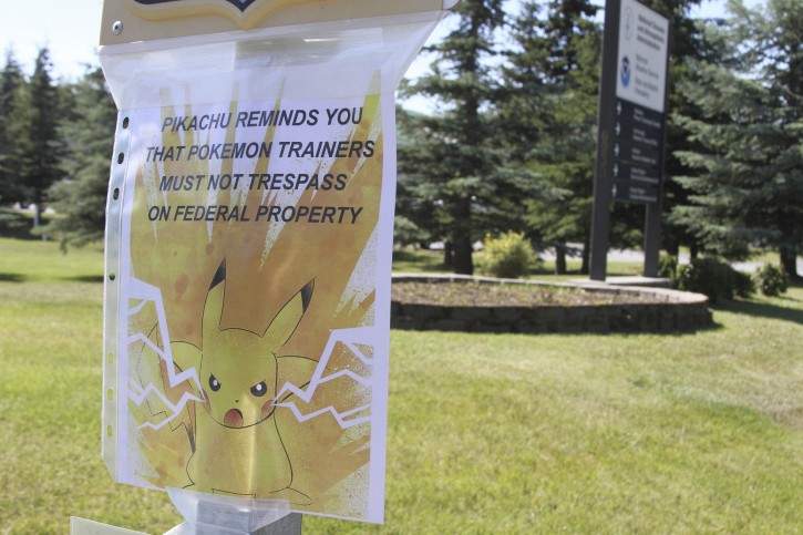 In this Tuesday, July 12, 2016 photo,, a sign is shown at the National Weather Service in Anchorage, Alaska, informing Pokemon players that it's illegal to trespass on federal property. The staff started noticing an uptick of people in the parking lot after the location was included as a gym in the popular game. The "Pokemon Go" craze across the U.S. has people wandering into yards, driveways, cemeteries and even an off-limits police parking lot in search of cartoon monsters, prompting warnings that trespassers could get arrested or worse. (AP Photo/Mark Thiessen)