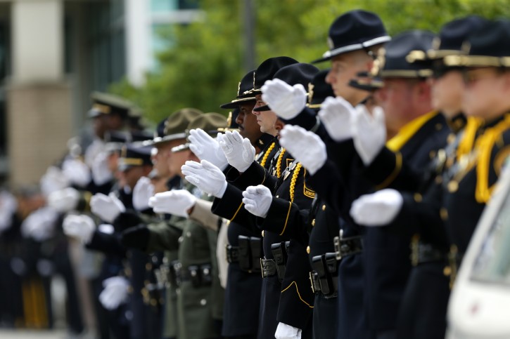 Members of a police honor guard raise their hands in salute as the casket of Baton Rouge police officer Matthew Gerald exits the Healing Place Church after funeral services in Baton Rouge, La., Friday, July 22, 2016. Multiple police officers were killed and wounded Sunday morning in a shooting near a gas station in Baton Rouge, less than two weeks after a black man was shot and killed by police here, sparking nightly protests across the city. (AP Photo/Gerald Herbert)