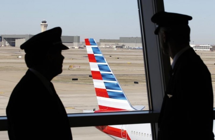 FILE - Pilots talk as they look at the tail of an American Airlines aircraft at Dallas-Ft Worth International Airport February 14, 2013.  Reuters