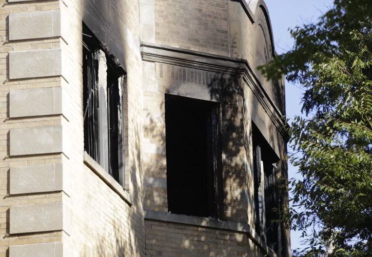 Charred and broken widows can be seen on the third floor of an apartment building where a fire that appears to have been deliberately set, killed multiple people, Tuesday, Aug. 23, 2016, in Chicago. (AP Photo/M. Spencer Green)
