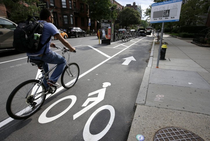 In this Tuesday, Aug. 16, 2016 photo a cyclist enters a bike lane that is routed between parked cars and the sidewalk, right, in Boston. Chicago, New York, Boston, and other U.S. cities are reconfiguring bike lanes to make them safer in light of a spate of fatal accidents involving cyclists and cars. (AP Photo/Steven Senne)