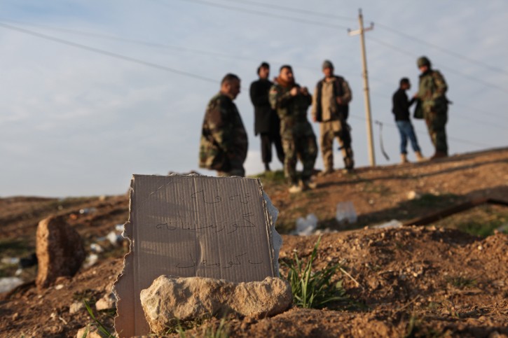 In this Monday, Dec. 22, 2014 photo, Kurdish Peshmerga forces inspect a site marked in Kurdish with a sign reading, 