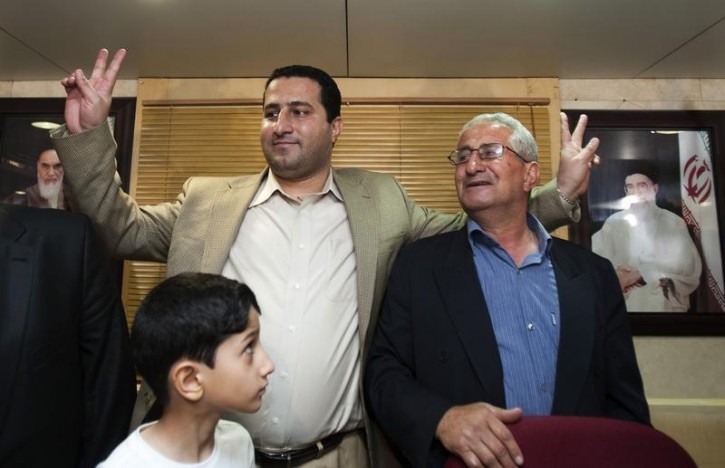 FILE - Iranian scientist Shahram Amiri flashes victory signs beside his father after a news conference at the Imam Khomini airport in Tehran July 15, 2010.  Reuters