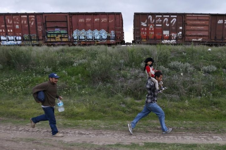 FILE - A Salvadoran father (R) carries his son while running next to another immigrant as they try to board a train heading to the Mexican-U.S. border, in Huehuetoca, near of Mexico City, June 1, 2015.  AP