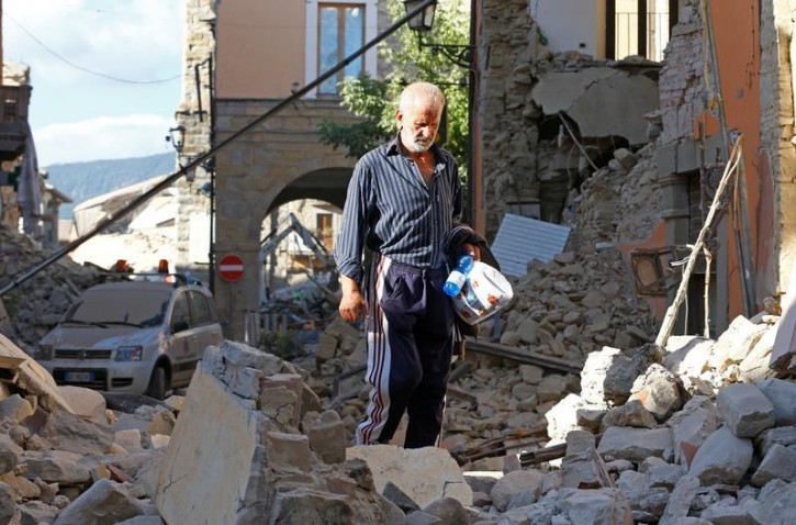 A man walks through rubble following an earthquake in Amatrice, central Italy, August 24, 2016. REUTERS/Stefano Rellandini