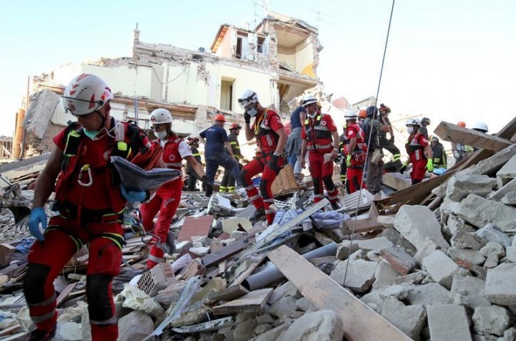 Rescuers walk through rubble following the earthquake in Amatrice, central Italy, August 24, 2016. REUTERS/Stefano Rellandini 