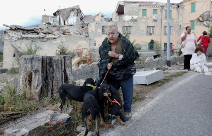 A man stands with dogs following an earthquake in Amatrice, central Italy, August 24, 2016. Picture taken August 24, 2016. REUTERS/Remo Casilli 