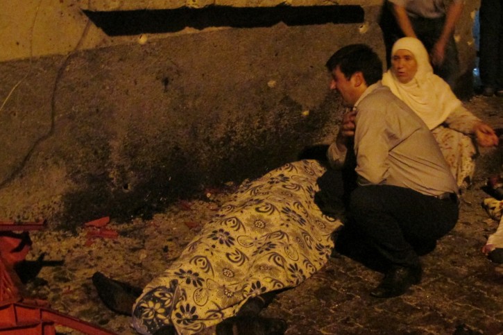 A man cries over a covered body after an explosion in Gaziantep, southeastern Turkey, late Saturday, Aug. 20, 2016. Gaziantep Province Gov. Ali Yerlikaya said the deadly blast, during a wedding near the border with Syria, was a terror attack. (IHA via AP)