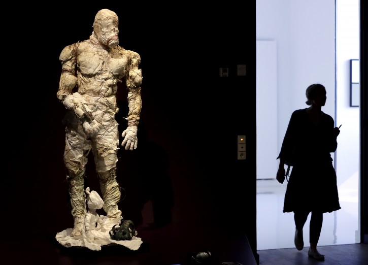 A woman walks past a Golem costume of the Malenki Theater in Tel Aviv as she arrives for a press presentation for the 'Golem' exhibition at the Jewish Museum in Berlin, Germany, Thursday, Sept. 22, 2016. (AP Photo/Michael Sohn)