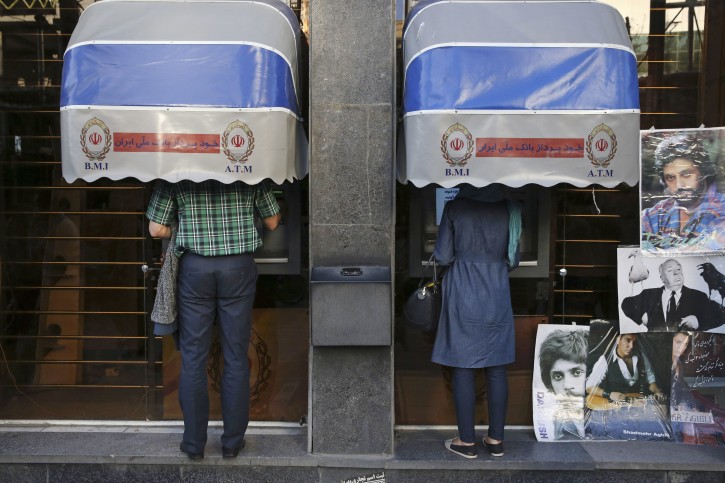 FILE -- In this April 4, 2015 file photo, Iranians use ATM machines of Bank Melli Iran in downtown Tehran, Iran. Iranian media are saying the country's banks will begin issuing credit cards for the first time in decades. AP Photo/Vahid Salemi, File)