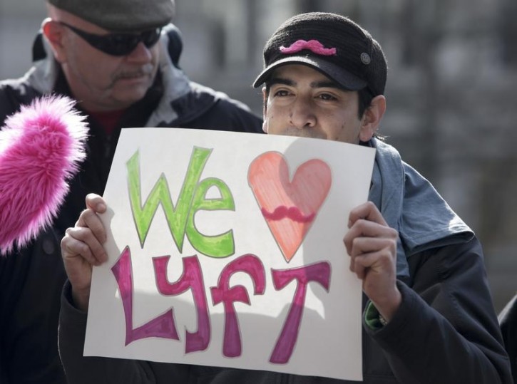 Frankie Roeder, 28, hows his support as Lyft ride-sharing supporters rally at City Hall in Seattle, Washington, US, February 12, 2014.    REUTERS/Jason Redmond/File photo